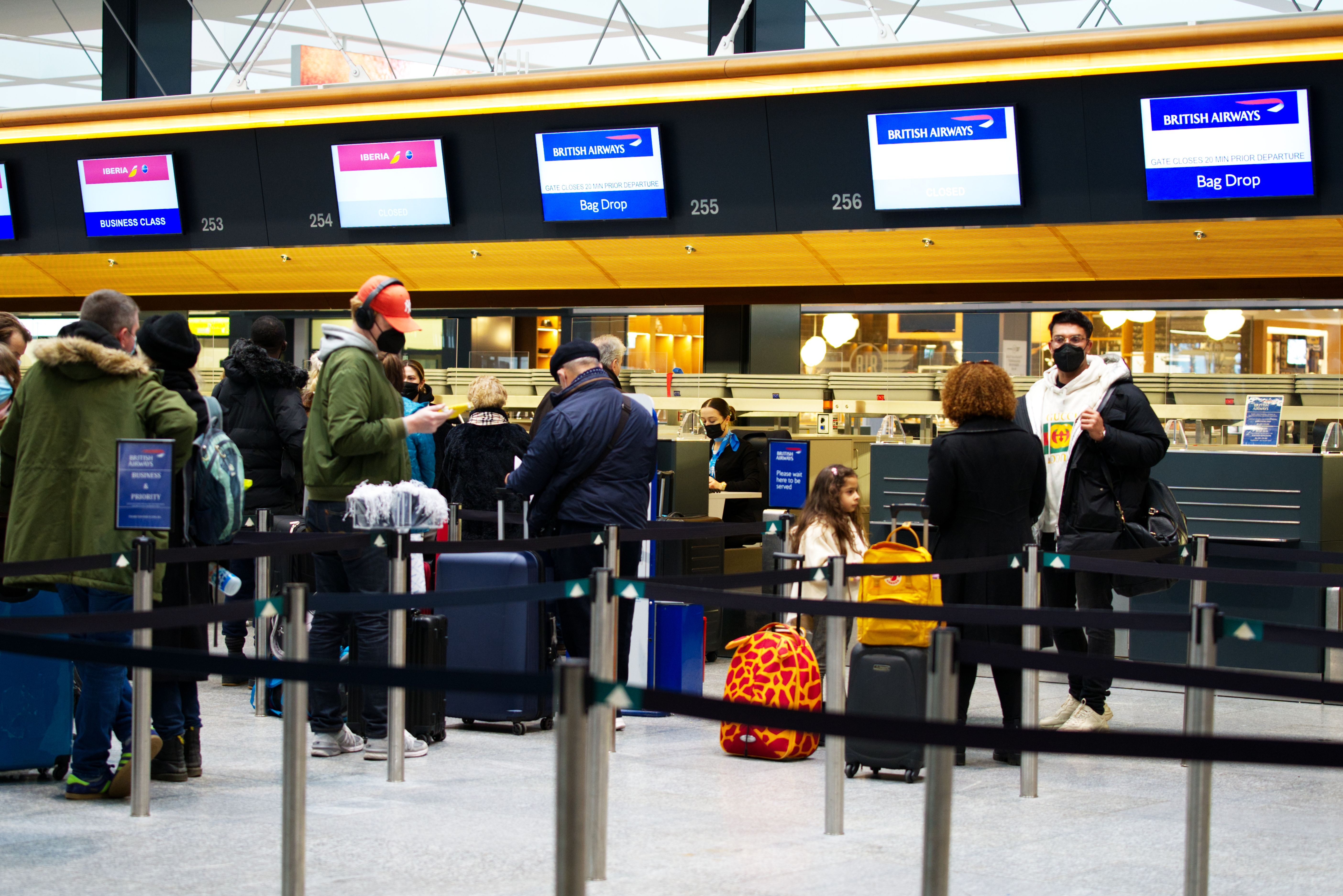 Passengers with luggage line up at Iberia's and British Airways' check in counters.