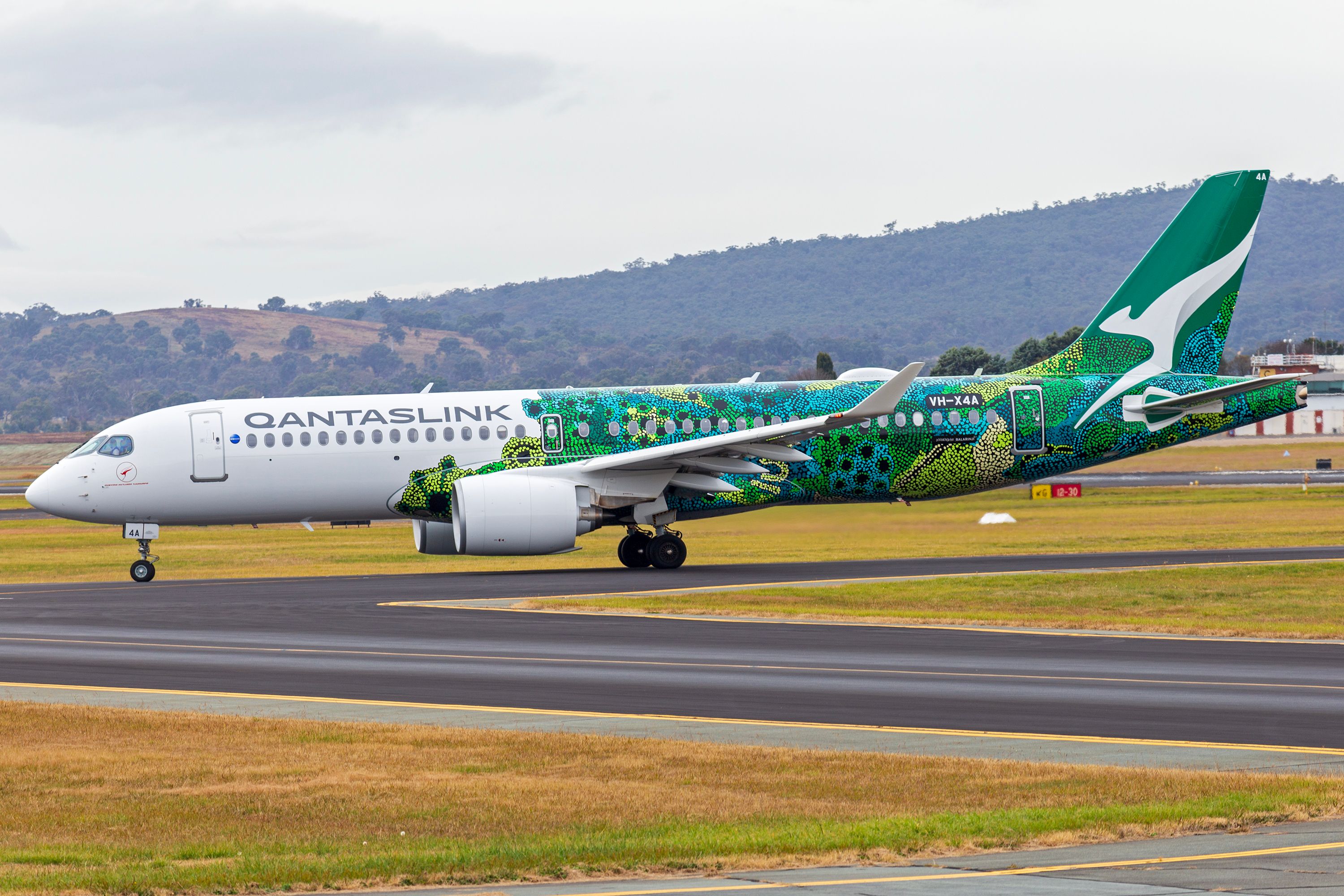 QantasLink,_operated_by_National_Jet_Systems,_(VH-X4A)_Airbus_A220-300_taxiing_at_Canberra_Airport