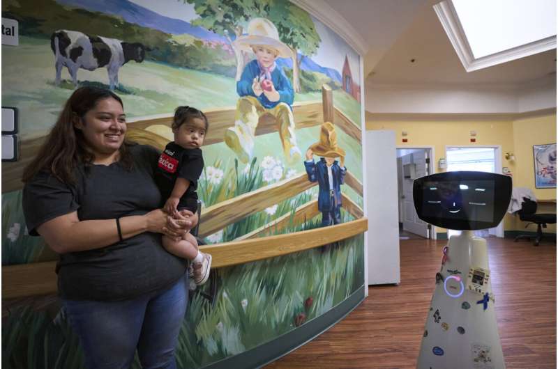 Robin the Robot, developed by Expper Technologies, interacts with Erica Ruiz and her daughter, Valentina, at the HealthBridge Orange Specialty Pediatric Hospital in Orange, Calif., on Friday, Sept. 12, 2025. Credit: AP Photo/Damian Dovarganes A robot programmed to act like a 7-year-old girl works to combat fear and loneliness in hospitals