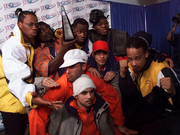 Group of artists crouched and gathered to pose for a photograph, some at the back holding a statue.