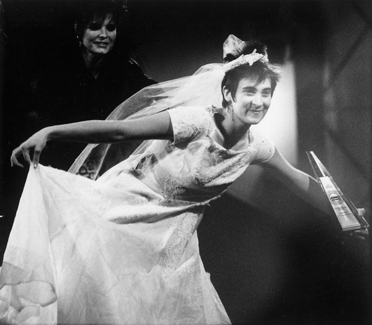 A person in a white wedding dress at an awards podium.