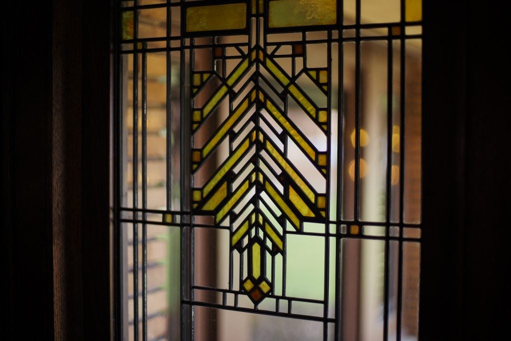 Geometric stained glass window with yellow and green art glass pattern.