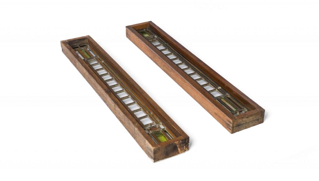 Pair of narrow stained glass window panels in weathered wooden frames.