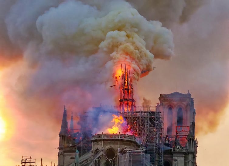 A medieval cathedral on fire against a smoke-filled sky.