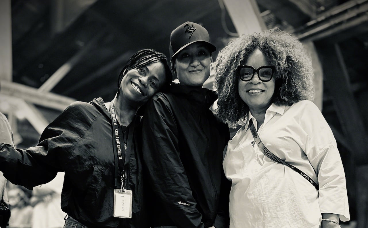 Black and white photo of three women standing and smiling at the camera.