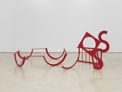 A floor sculpture with red curlicues of steel.