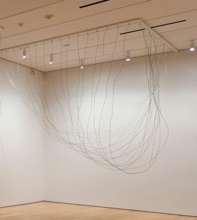 A sculpture featuring barbed wire hanging down from the ceiling.