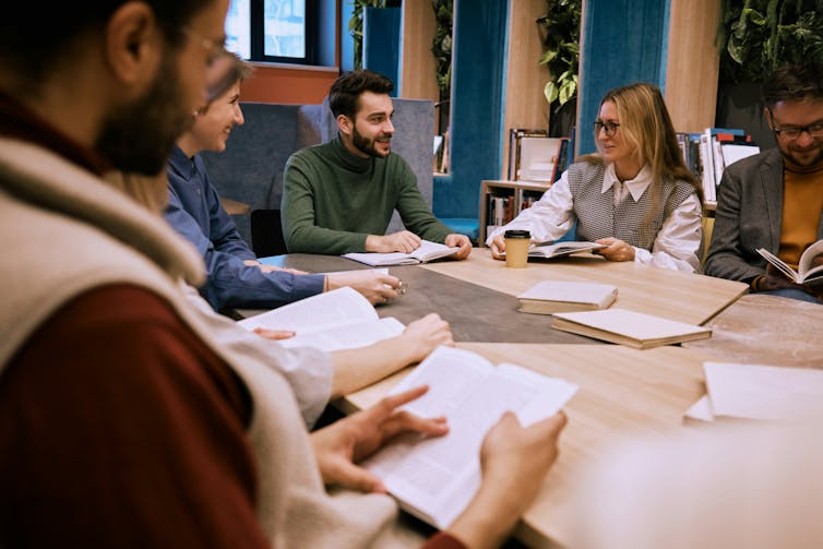A group of young adults sitting around a table with open books in front of them
