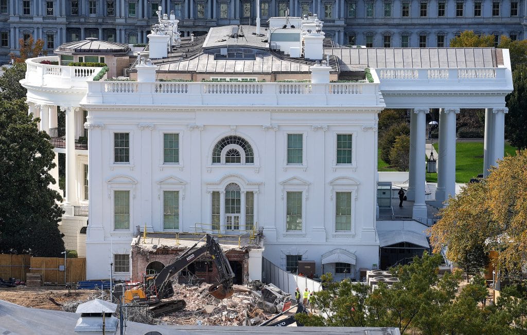 Excavators demolish lower section of White House East Wing while workers oversee debris and construction barriers trump
