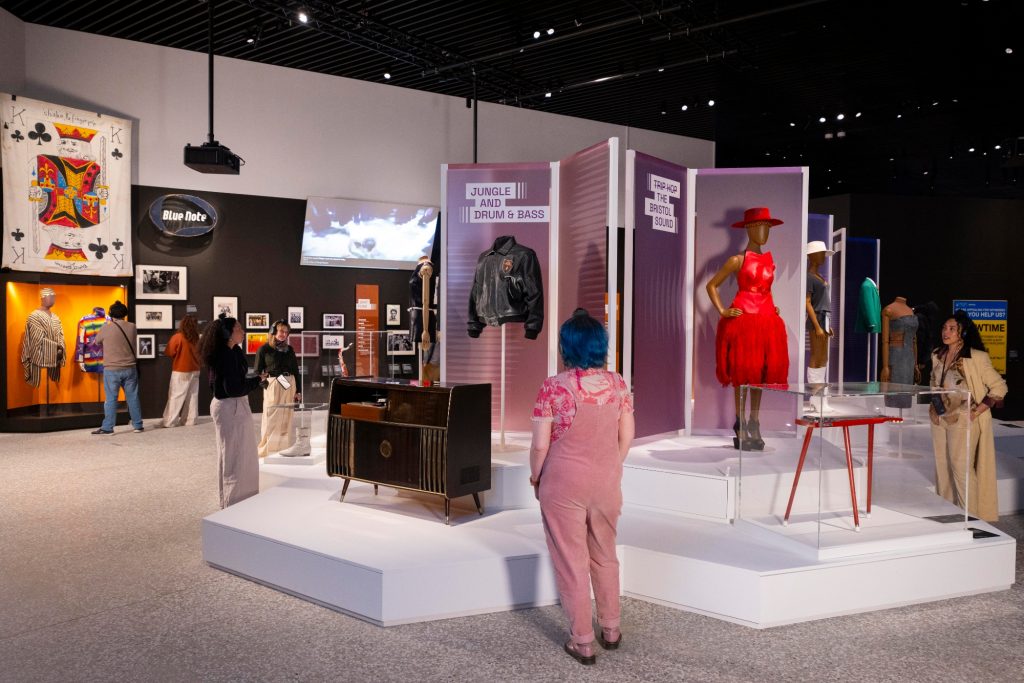 a museum interior contains outfits on mannequins and other items related to music mounted on displays and platforms