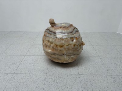 A rough-hewn orb-like sculpture in a light-colored stone.