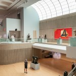 A photo shows a high-ceilinged art museum gallery with numerous modern artworks on display and skylights bringing in daylight