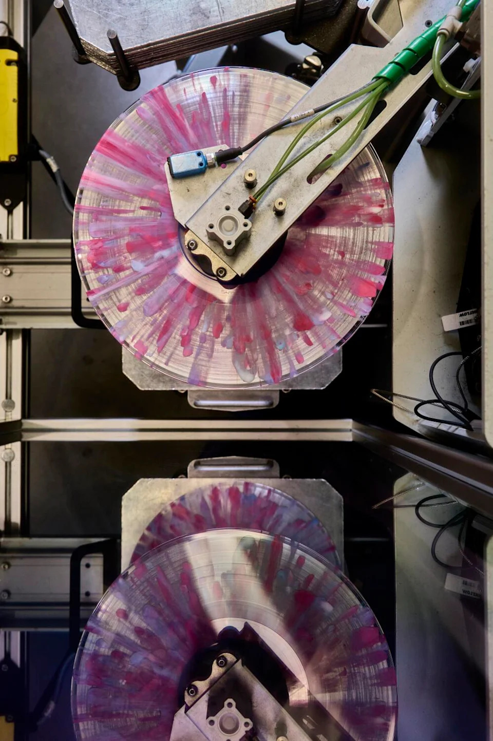 Pink, purple, and blue splatter-patterned records being prepared for trimming.