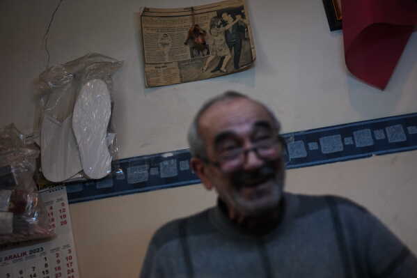A newspaper clipping hangs on the wall behind Hasan Saglam as he works in the workshop of tango shoe brand Necmi Usta, in Istanbul, Turkey, Wednesday, Jan. 21, 2026. (AP Photo/Francisco Seco)