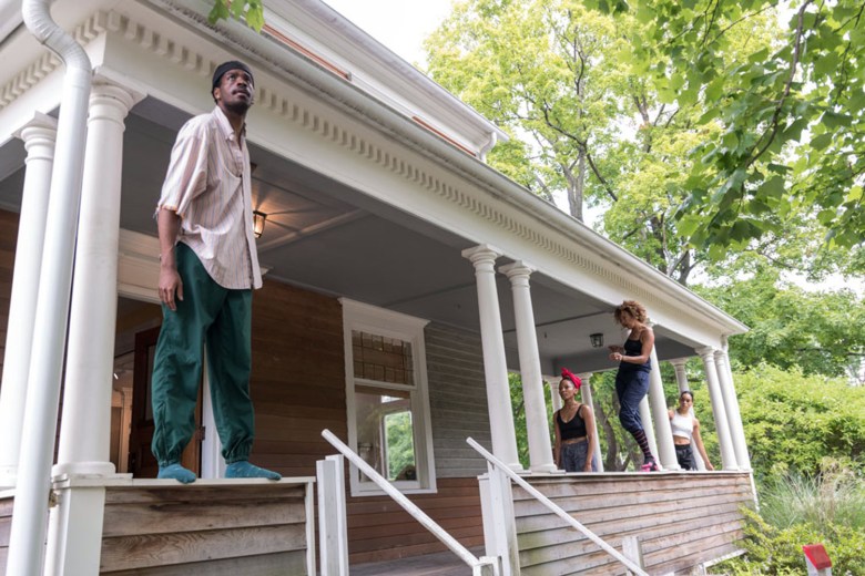 Four dancers stand on the porch of the John Brown House in Akron, Ohio, during a dance performance.