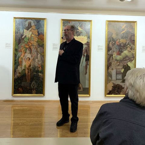 male figure in black in front of triptych