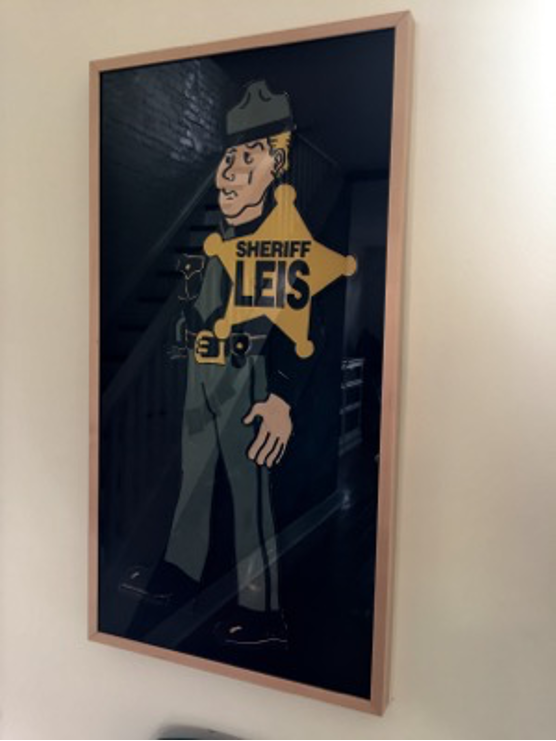 A cutout of a male figure with a star on his uniform reading Sheriff Leis.