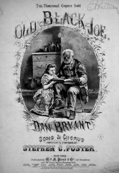 Sheet music cover featuring text 'Old Black Joe' and an image of an elderly Black man sitting a chair reading to a white girl kneeling by his side.