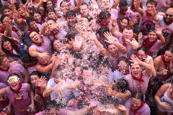 Revelers celebrate as the txupinazo, the traditional rocket marking the start of the San Fermín festival, kicks off nine days of uninterrupted festivities in Pamplona, Spain, Monday, July 6, 2026. (AP Photo/Miguel Oses)