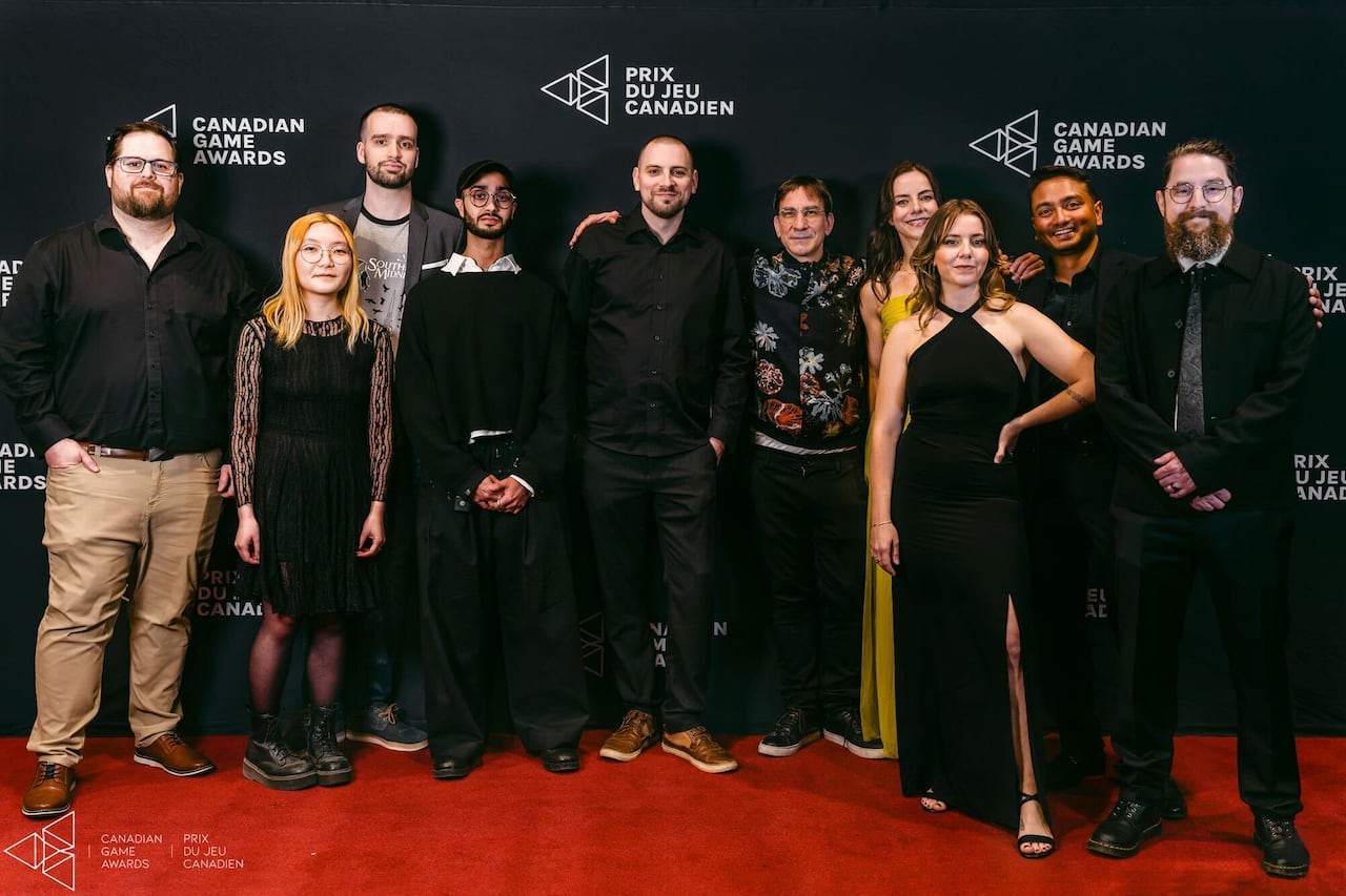 On a red carpet and against a black backdrop that says "Canadian Game Awards," a group of 10 people wearing formal attire stand in a line.
