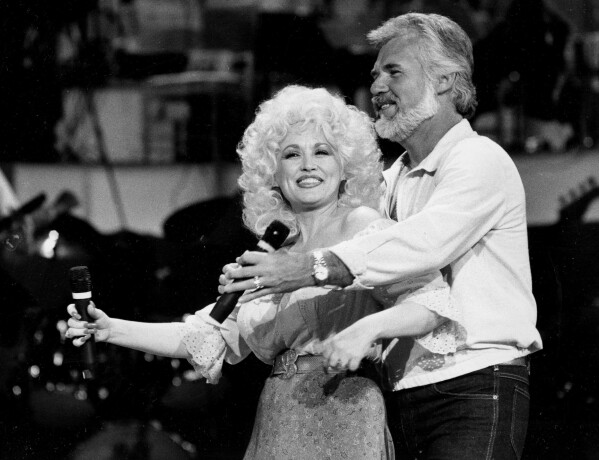 Dolly Parton, left, and Kenny Rogers rehearse a song for their appearance on the TV show "Live... And in Person" in Los Angeles on Sept. 27, 1983. (AP Photo/Doug Pizac, File)