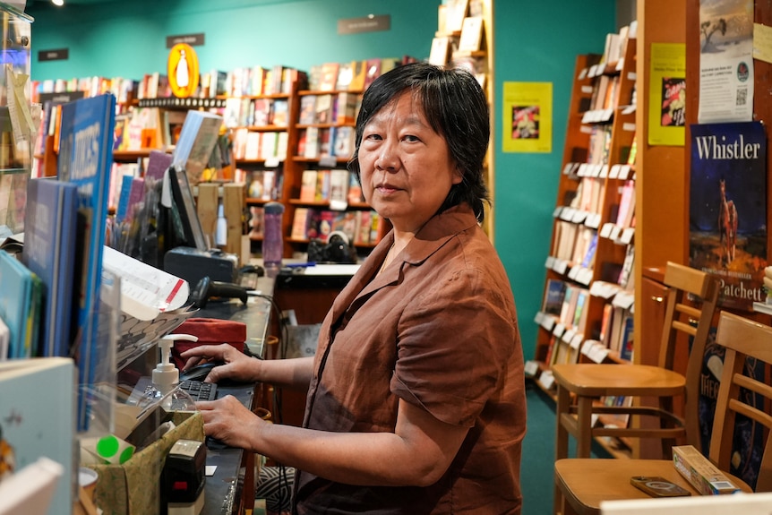 Jaye Chin-Dusting on a computer, behind the desk of her bookstore