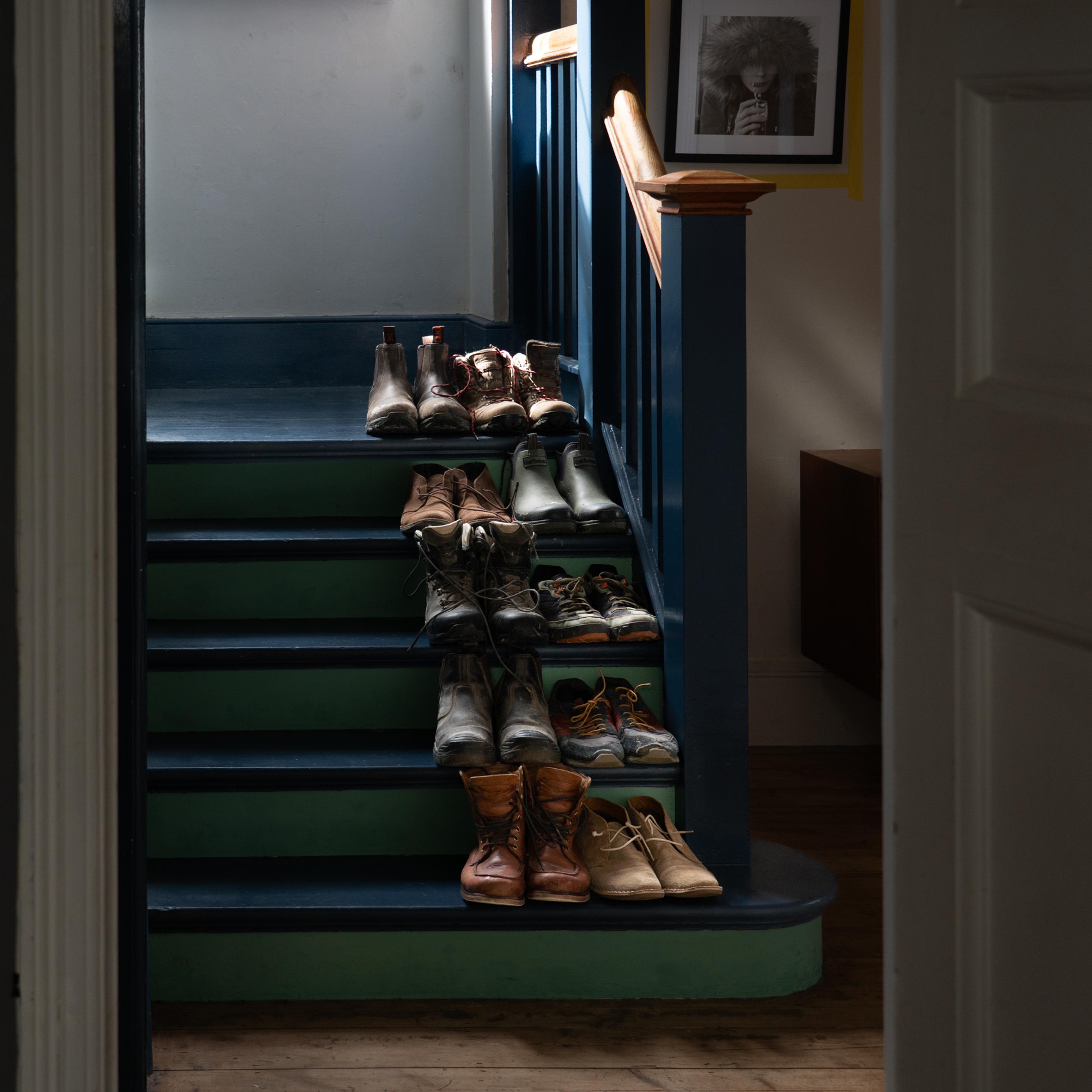 A dimly lit staircase with multiple pairs of shoes neatly arranged on each step.
