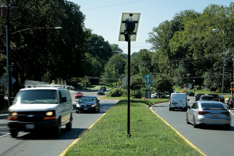 Cars drive by a grass covered median.