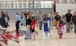 Nakotah Reynolds (center) holds his older sister Kailee’s hand and wears his noise-dampening headphones during the accessibility-focused special his family held during the South Sound Powwow on Sept. 26, 2026. Nakotah is autistic and sometimes finds the loud drumming and singing and parts of the required regalia of a powwow overstimulating, so holding a special that allows accommodations lets him participate in the dancing.
