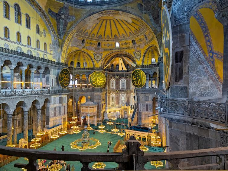 An ornate building featuring golden domed ceilings and a green floor.