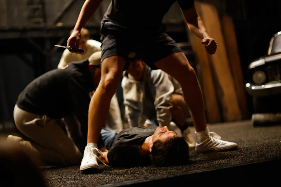 Actors rehearse fight choreography on a stage.