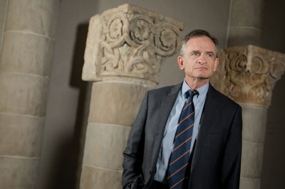 A man standing next to very old columns.