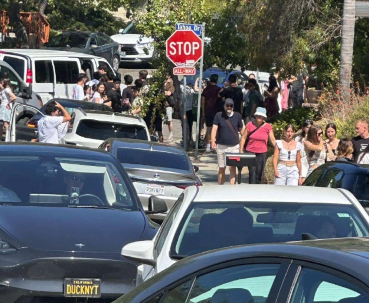 Crowds walk alongside cars in a street clogged with traffic.