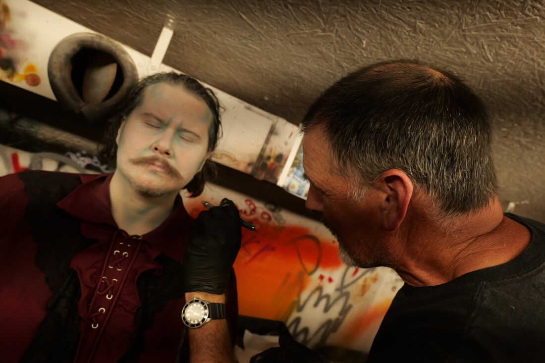 Robert Doyle (left) sits still as Markoff's art director and makeup manager Chris Knowles (right) goes to work.